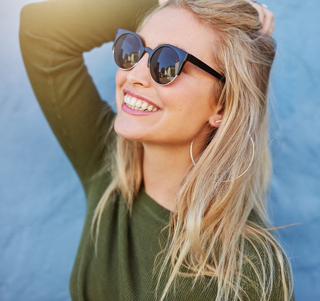 Smiling young woman with sunglasses looking upwards