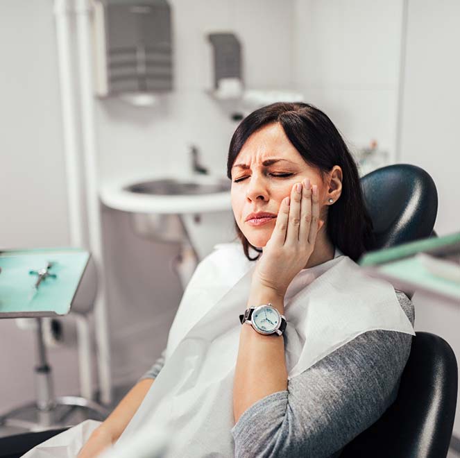 Woman holding cheek while visiting Jacksonville emergency dentist