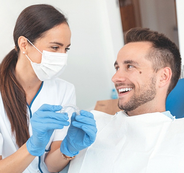 Male patient with female dentist holding Invisalign in Jacksonville, FL