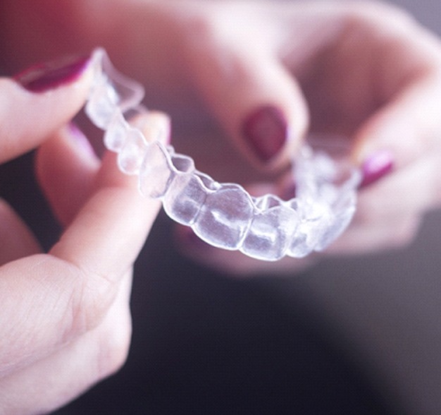 Two hands with an Invisalign aligner