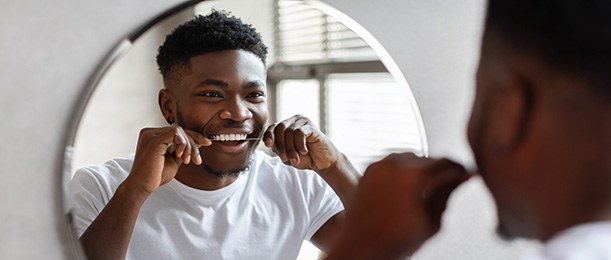 Man smiling while flossing his teeth