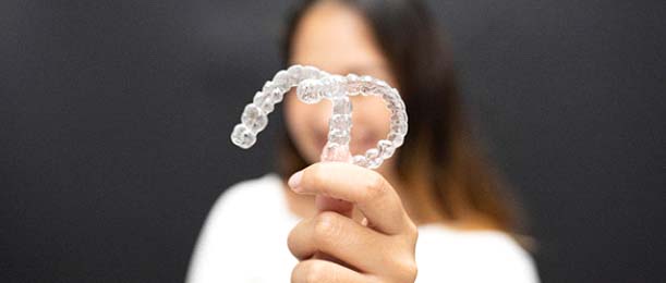 young woman holding two clear aligners