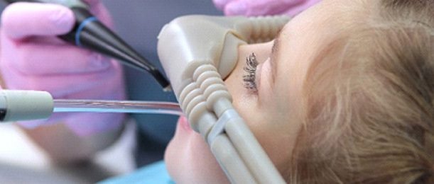 A young girl receiving nitrous oxide while a dentist works in Riverside