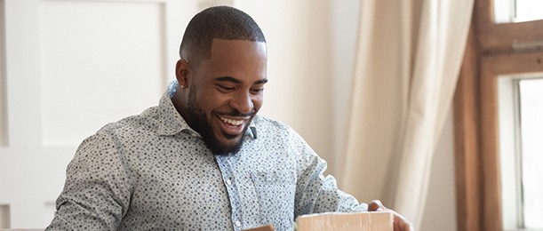 Man sitting on couch looking at open package