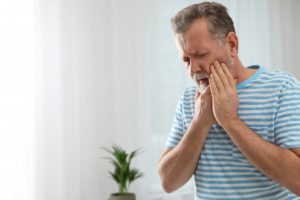 man suffering from strong tooth pain at home